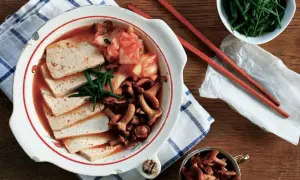 Zupa Kimchi Jjigae z tofu, grzybami i szczypiorkiem w misce.