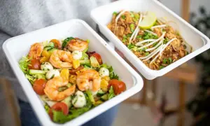 Dwa pojemniki z jedzeniem na wynos: sałatka z krewetkami i makaron Pad Thai.