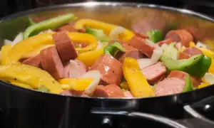 Kiełbasa z papryką i cebulą smażona na patelni.