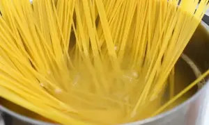 Surowe spaghetti w garnku z gotującą się wodą.