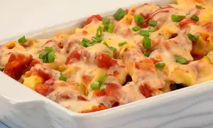 Zapiekanka z tortellini, pomidorami i serem, posypana szczypiorkiem.