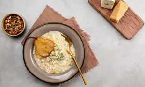Risotto z gruszką i serem pleśniowym, obok orzechy i kawałki parmezanu.