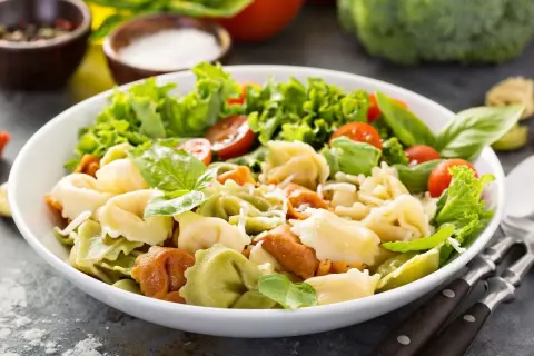 Sałatka z kolorowymi tortellini, pomidorkami koktajlowymi, sałatą i bazylią.