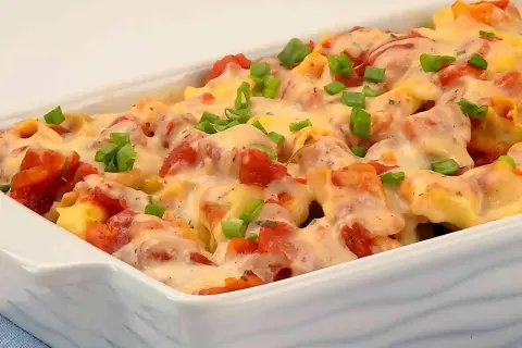 Zapiekanka z tortellini, pomidorami i serem, posypana szczypiorkiem.