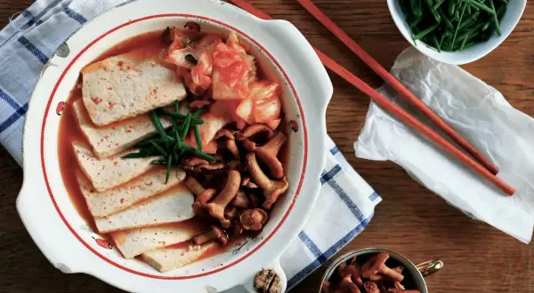Zupa Kimchi Jjigae z tofu, grzybami i szczypiorkiem w misce.