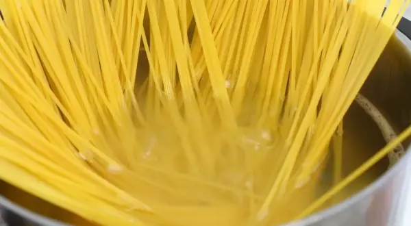 Surowe spaghetti w garnku z gotującą się wodą.