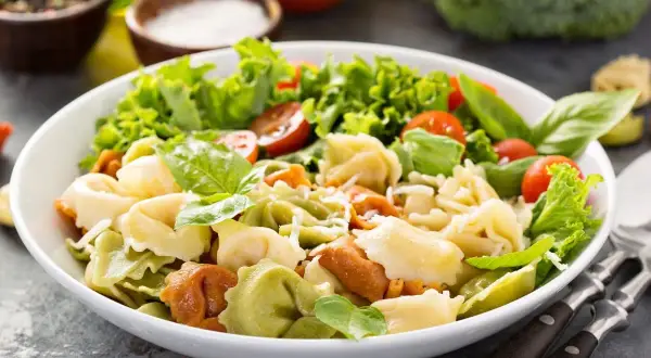 Sałatka z kolorowymi tortellini, pomidorkami koktajlowymi, sałatą i bazylią.