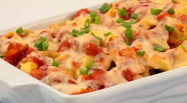 Zapiekanka z tortellini, pomidorami i serem, posypana szczypiorkiem.