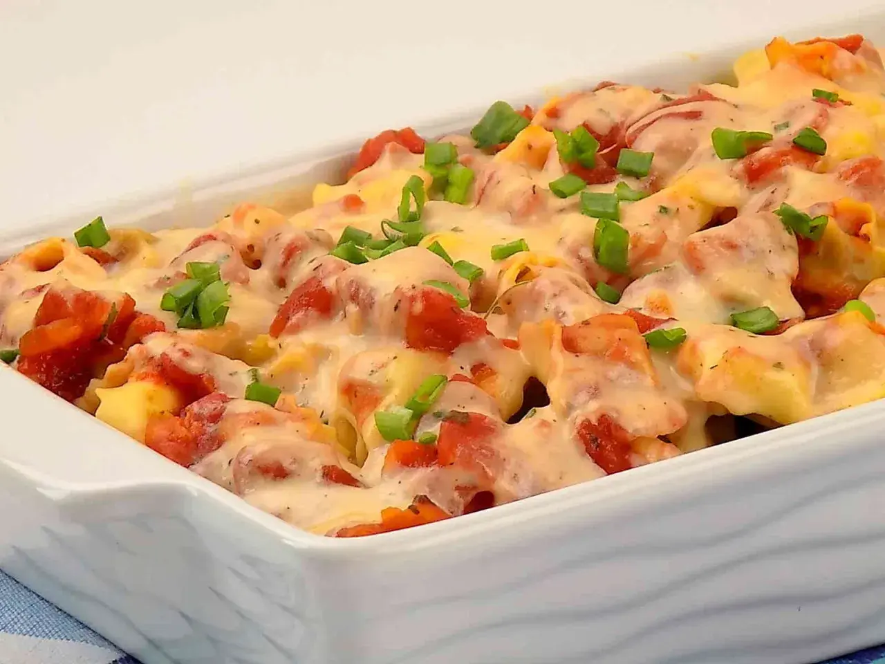 Zapiekanka z tortellini, pomidorami i serem, posypana szczypiorkiem.