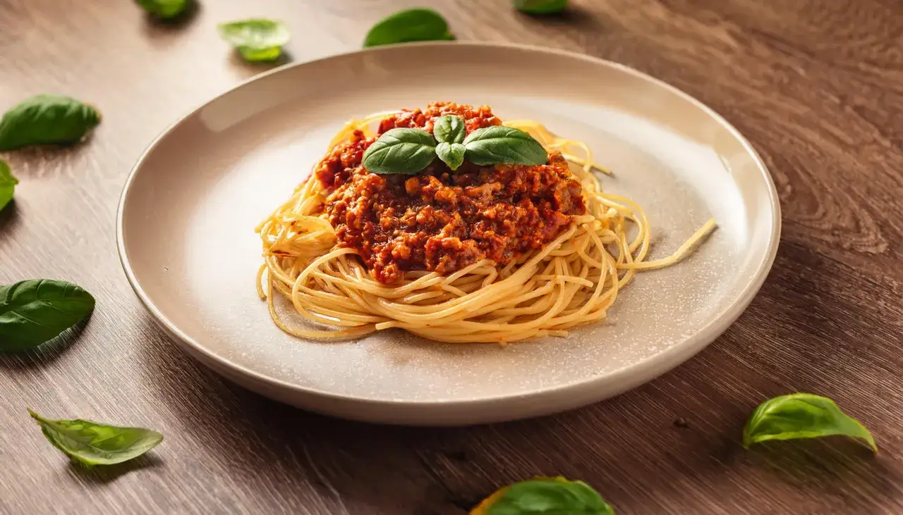 Gotowe spaghetti bolognese na talerzu z parmezanem i bazylią