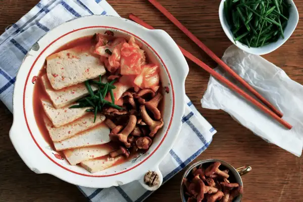 Zupa Kimchi Jjigae z tofu, grzybami i szczypiorkiem w misce.