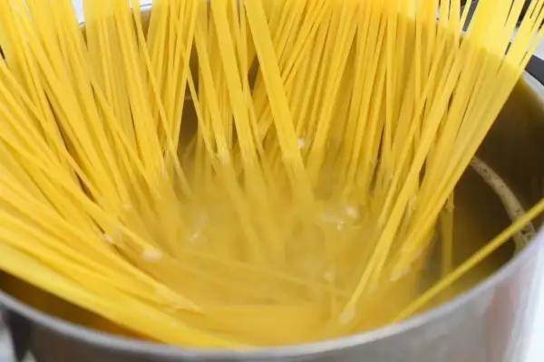 Surowe spaghetti w garnku z gotującą się wodą.