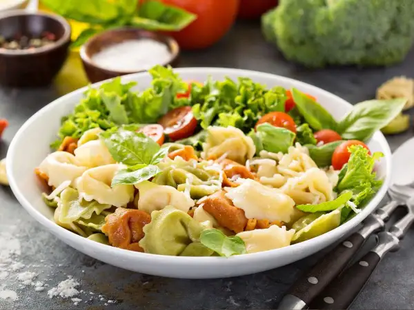 Sałatka z kolorowymi tortellini, pomidorkami koktajlowymi, sałatą i bazylią.