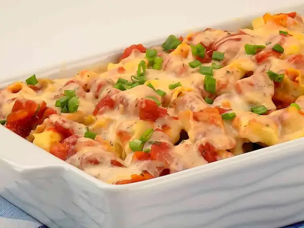 Zapiekanka z tortellini, pomidorami i serem, posypana szczypiorkiem.